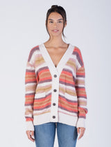 Model wearing a white, pink, purple, and orange striped cardigan and a pair of jeans.